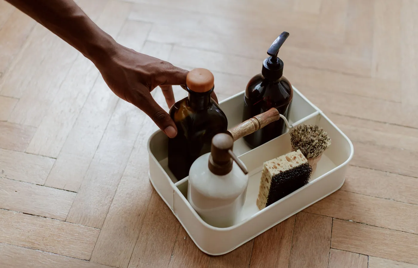 A hand reaching for a set of household cleaning bottles