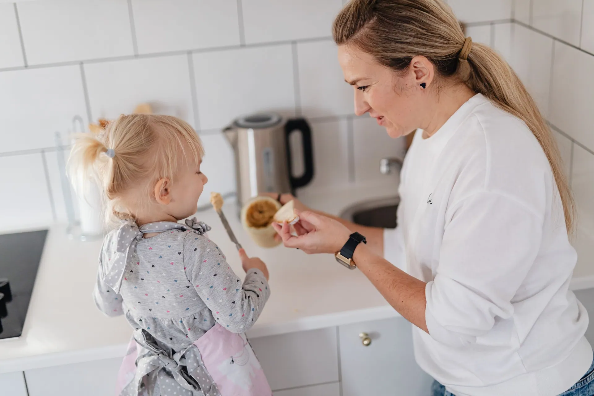 A mom and her toddler together at a bright kitchen counter