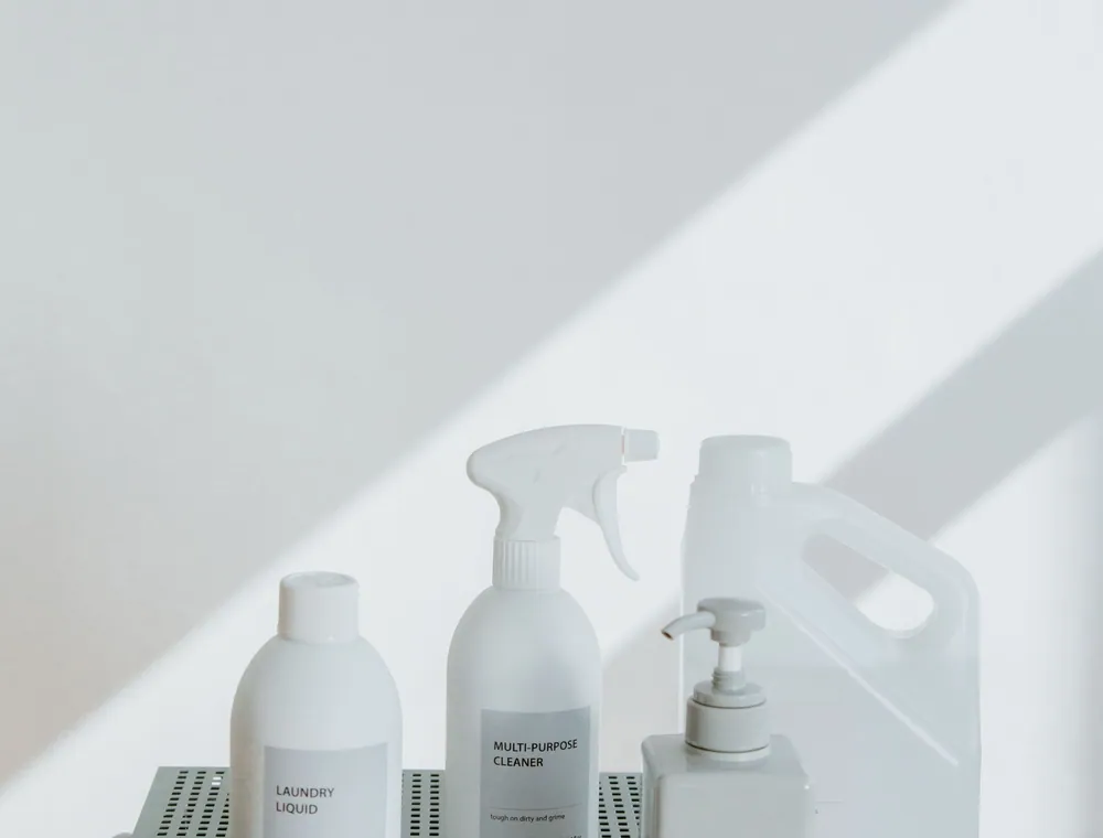 Simple unlabeled bottles on a sage-green cabinet in sunlight